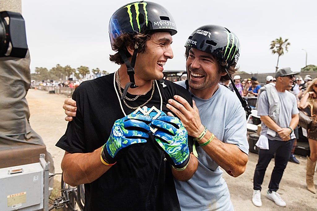 two X Games athletes wearing Monster Energy helmets celebrating together after a competition